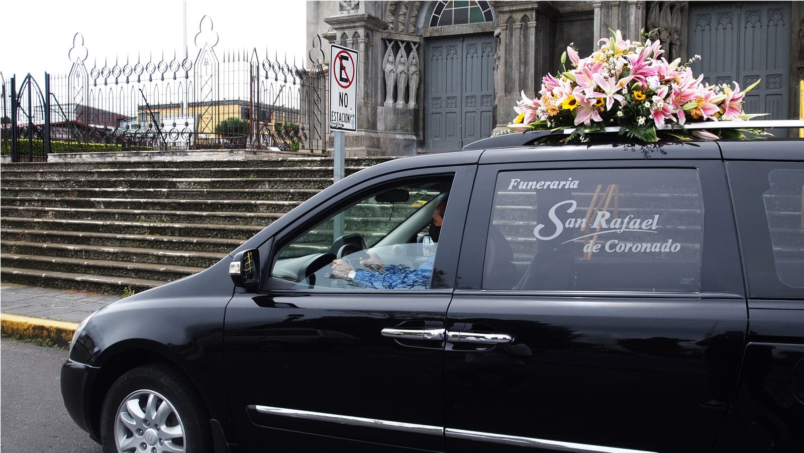 Carroza de Funeraria San Rafael frente a la iglesia, con conductor