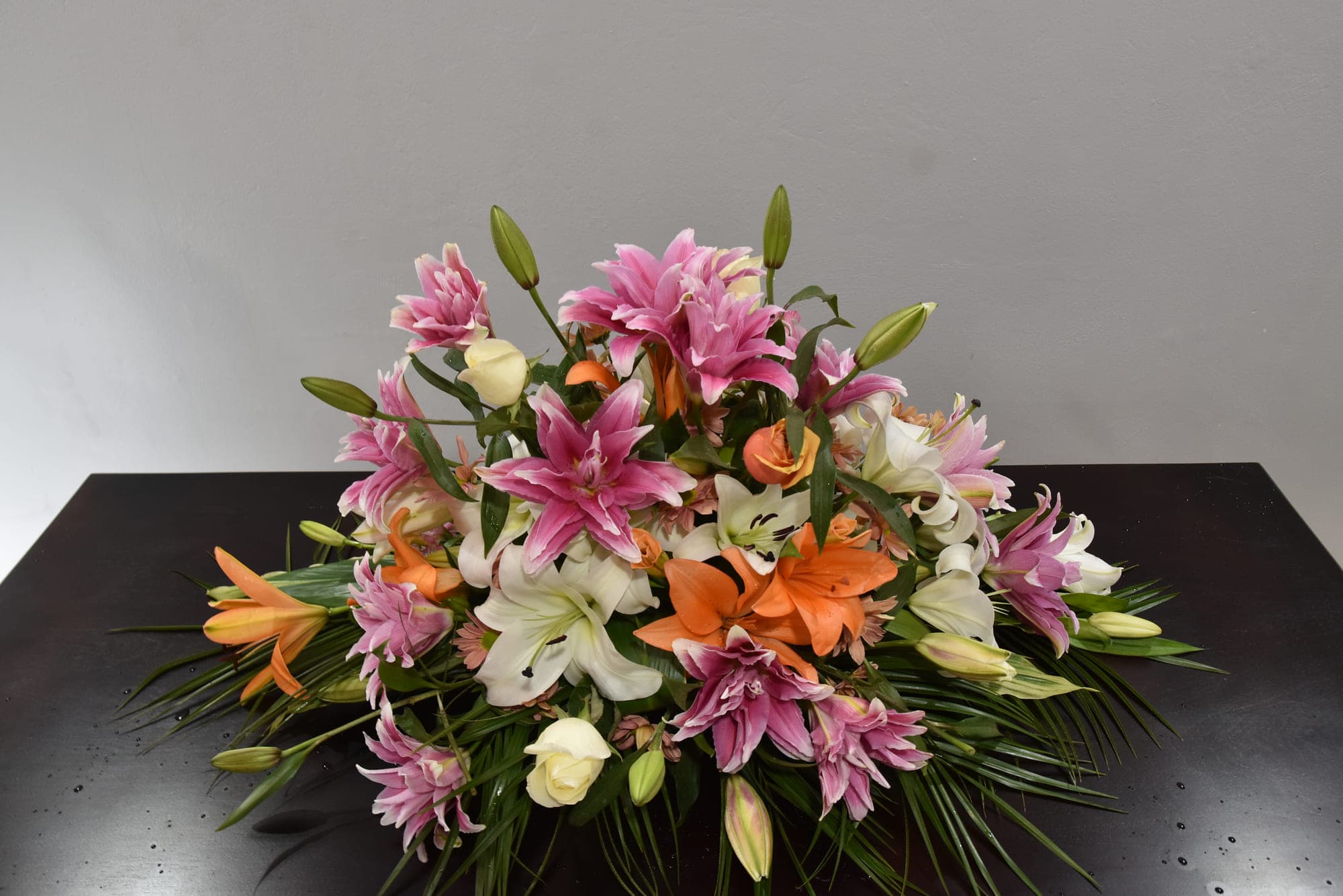 Arreglo floral de lirios y rosas preparado para una despedida